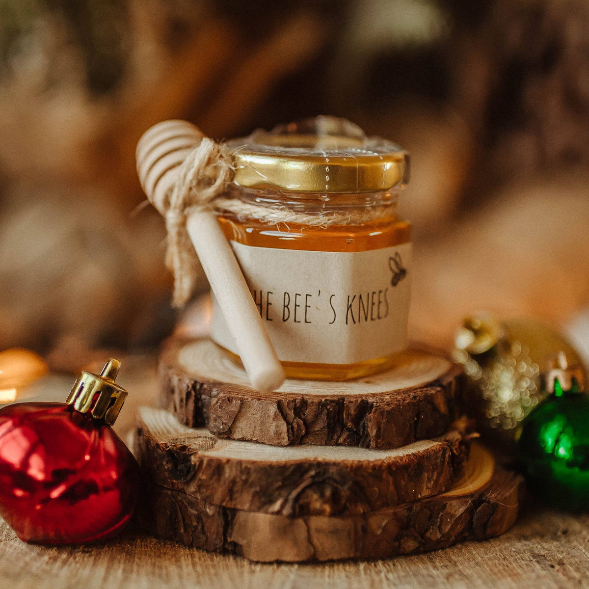 Jar of honey on a wooden stump with Christmas ornaments in a warm, blurred background
